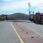 photo of wind turbine component being transported over median by truck