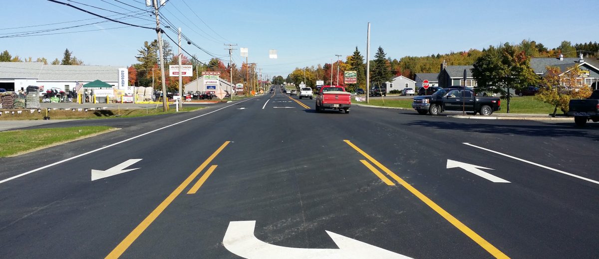 Photo of a freshly repaired road with white arrows and yellow lines