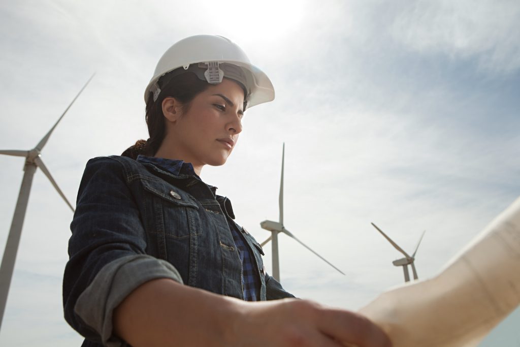 Female engineer at wind energy farm with plans