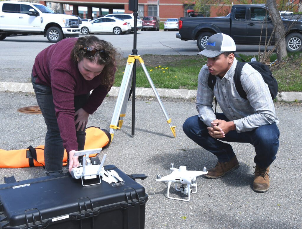 Katie Moran demonstrates drone calibration techniques to pilot Quinn Stamps
